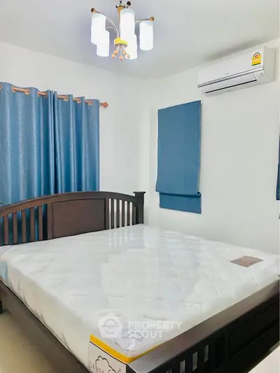 Spacious bedroom with elegant wooden bed and modern air conditioning unit.