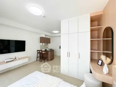 Modern studio apartment with stylish furniture and open layout, featuring a cozy bed, TV, and compact kitchen area.
