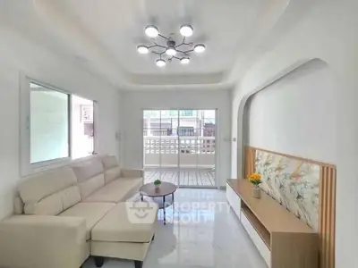 Spacious living room with modern lighting and large balcony access, perfect for relaxation and entertaining.