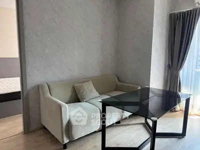 Modern living room with elegant sofa and glass table, featuring natural light and stylish decor.