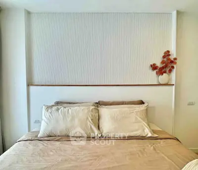 Modern bedroom with elegant decor and neutral tones, featuring a stylish headboard and decorative vase.