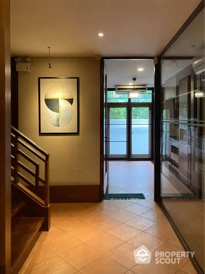 Elegant hallway with modern art and glass doors leading to a bright balcony.