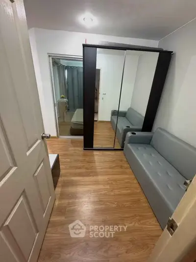 Modern bedroom with mirrored wardrobe and sleek gray sofa