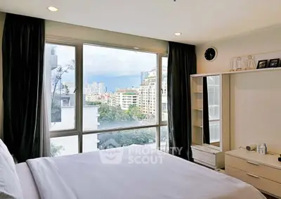 Spacious bedroom with large window offering stunning city views in modern apartment.