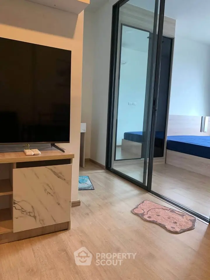 Modern apartment interior with sleek TV setup and cozy bedroom view.