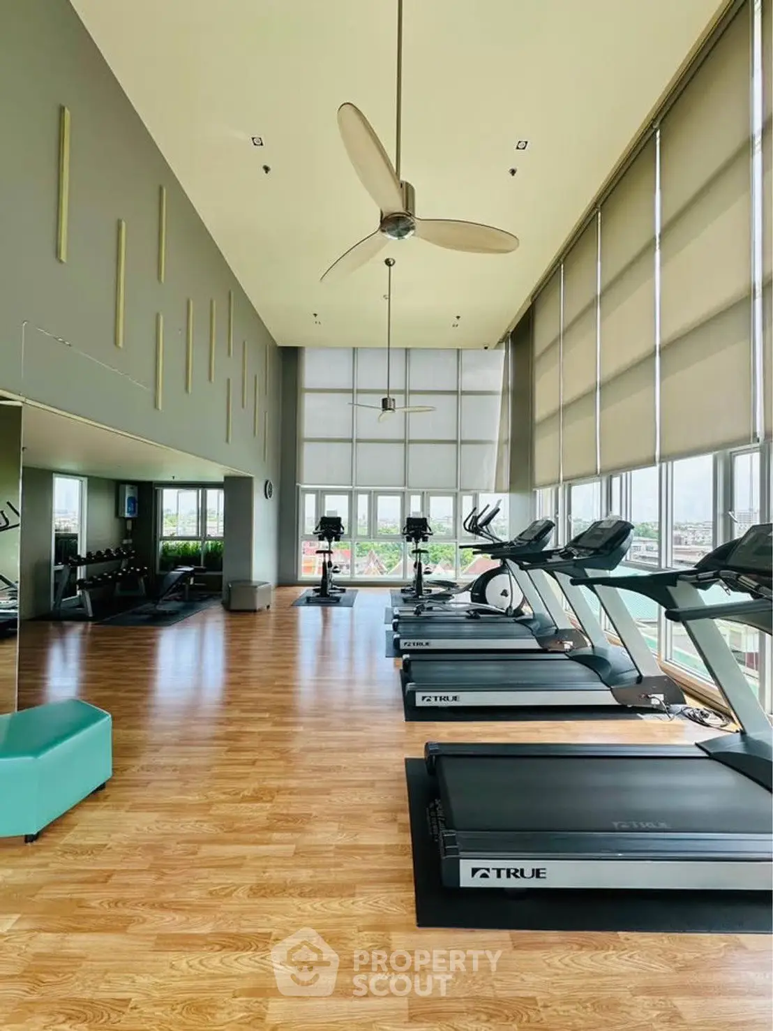 Spacious gym with modern equipment and large windows offering a panoramic view, perfect for fitness enthusiasts.