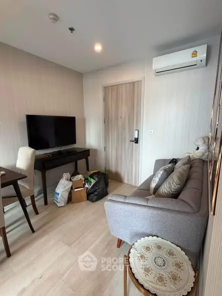 Cozy living room with modern decor, featuring a wall-mounted TV and air conditioning, perfect for relaxation.