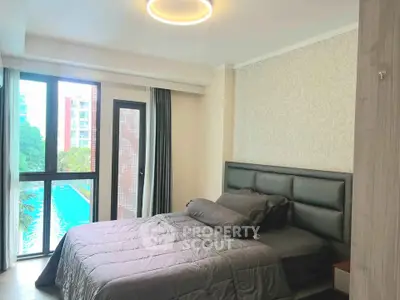 Luxurious bedroom with pool view, modern decor, and ample natural light in a high-end apartment.