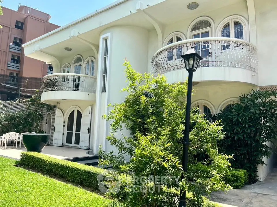 Elegant two-story house with curved balconies and lush garden