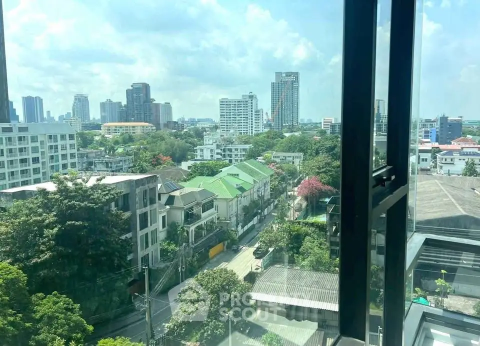 Stunning cityscape view from high-rise window showcasing urban skyline and lush greenery.
