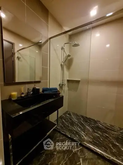 Luxurious modern bathroom with sleek black marble and glass shower enclosure.