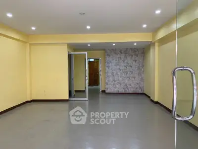 Spacious empty room with yellow walls and glass door, ideal for customization.