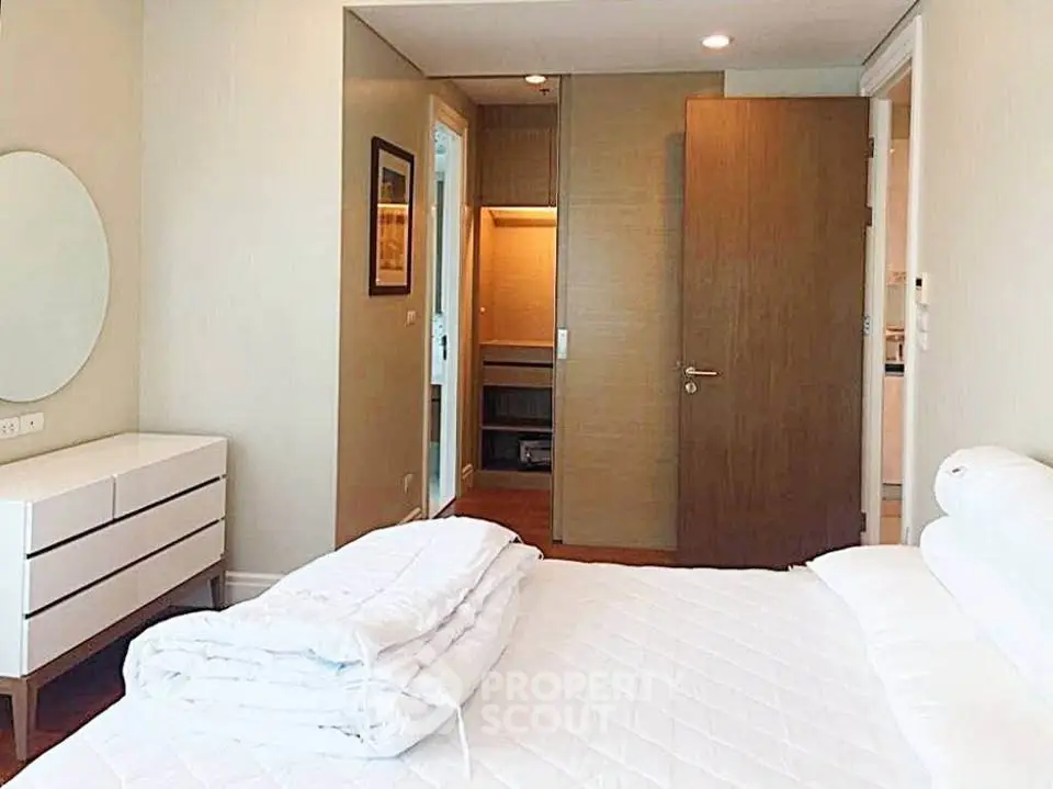 Spacious bedroom with modern furniture and walk-in closet in a luxury apartment.