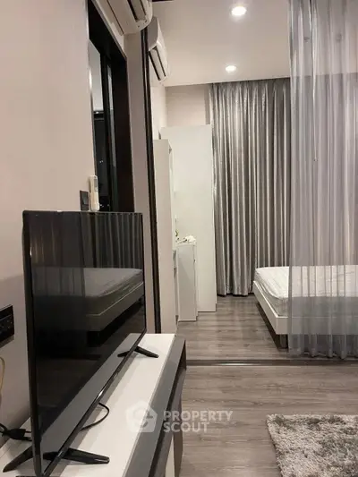 Modern studio apartment with sleek design, featuring a cozy bedroom and living area separated by a stylish curtain.