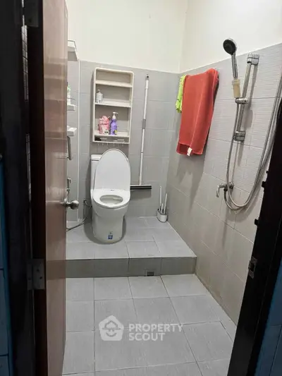 Compact bathroom with modern fixtures and tiled flooring, featuring a shower and toilet.