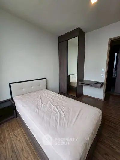 Modern bedroom with sleek wooden flooring and minimalist furniture design.