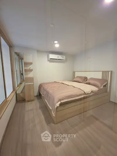 Cozy bedroom with modern wooden flooring and air conditioning, perfect for restful nights.