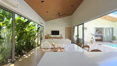 Luxurious open-plan living room with pool view and lush greenery