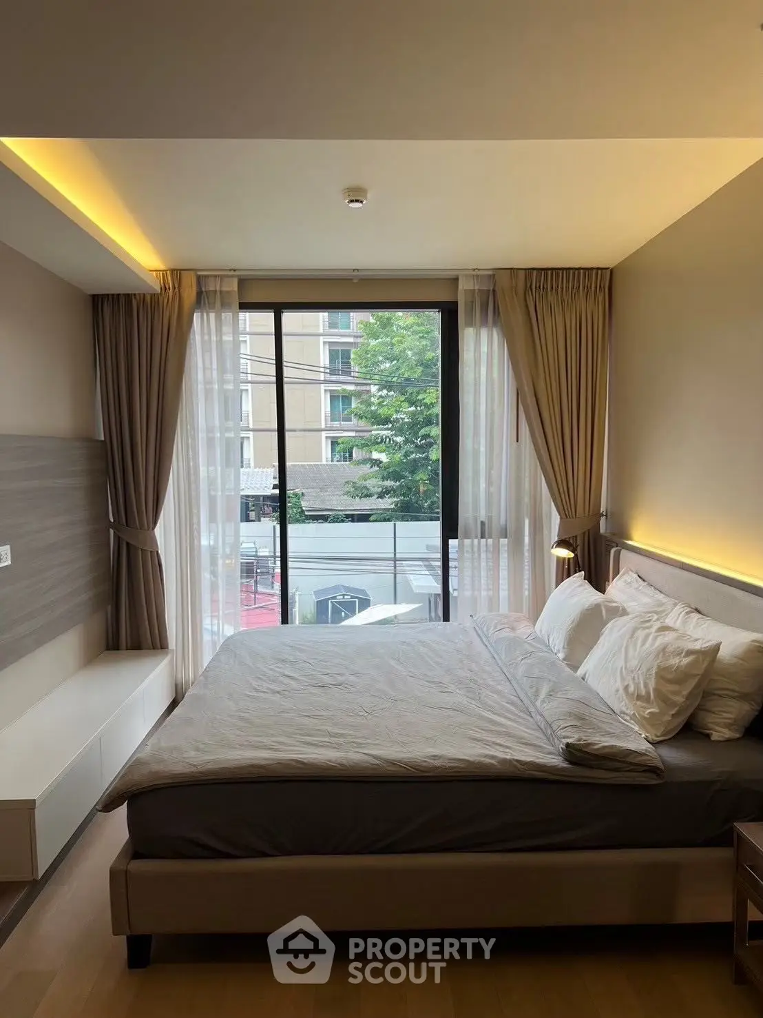 Modern bedroom with large window and elegant decor in urban apartment.