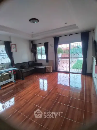 Spacious living room with polished wooden floors and large windows for natural light.