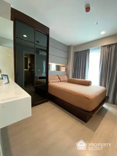 Elegantly furnished bedroom with a large bed, mirrored wardrobe, and modern decor, perfect for urban living.