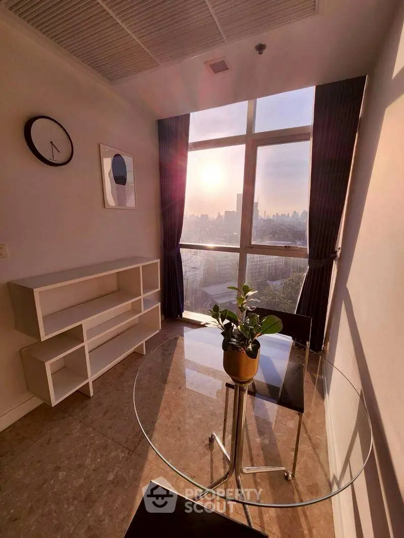 Chic study room with glass table and stunning city view at sunset.