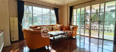Spacious living room with elegant orange sofas and large windows offering a bright, inviting atmosphere.