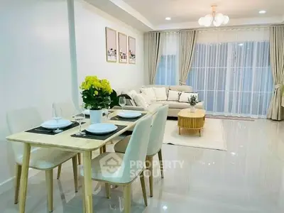 Elegant living room with dining area, modern decor, and natural light.