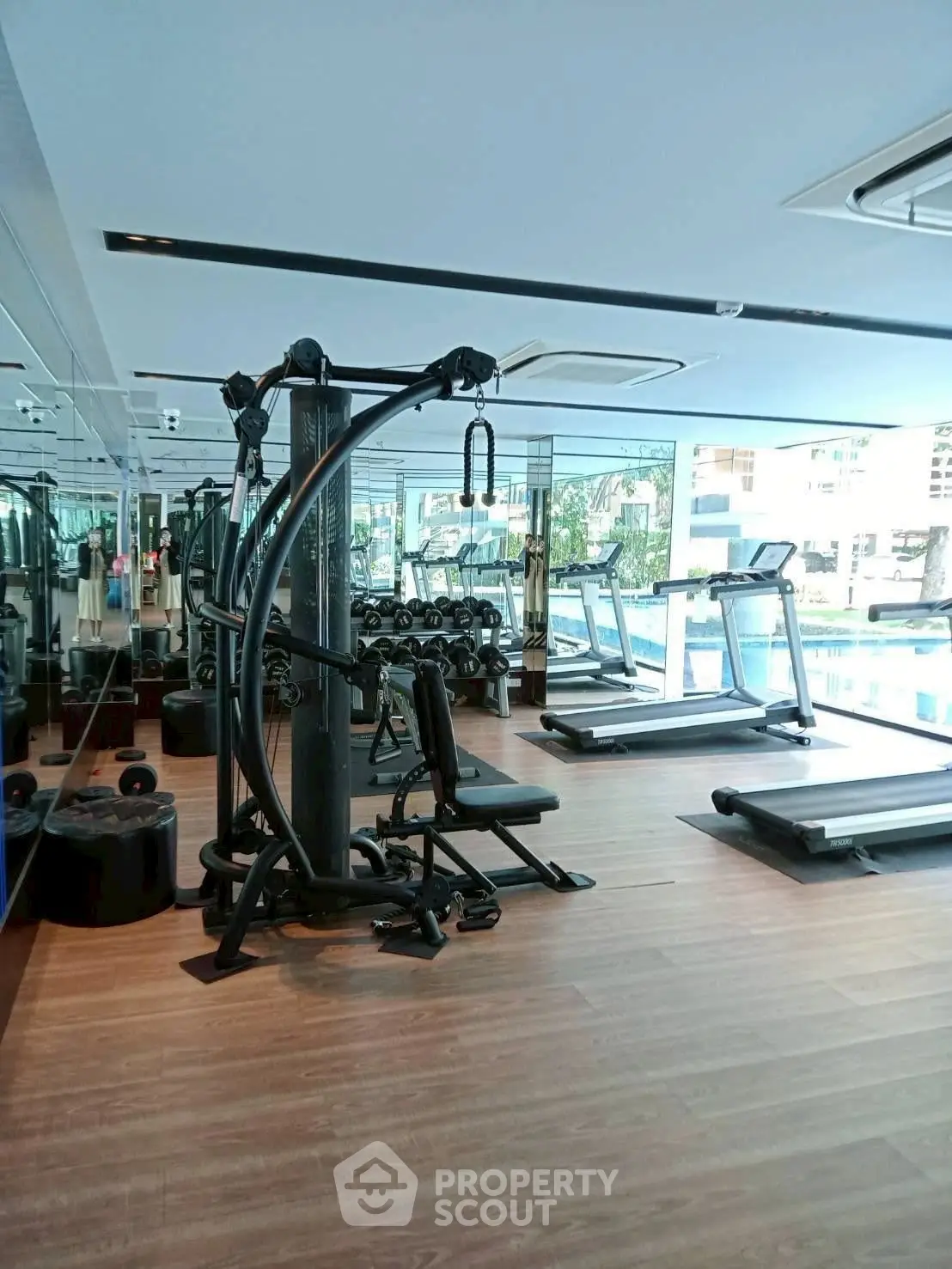 Modern gym with state-of-the-art equipment and pool view, perfect for fitness enthusiasts.