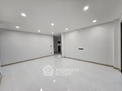 Spacious modern living room with bright lighting and sleek tile flooring.