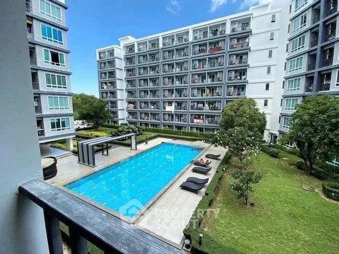 Modern apartment complex with pool and garden view from balcony.