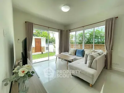 Bright and airy living room with garden view, featuring modern furniture and large windows.