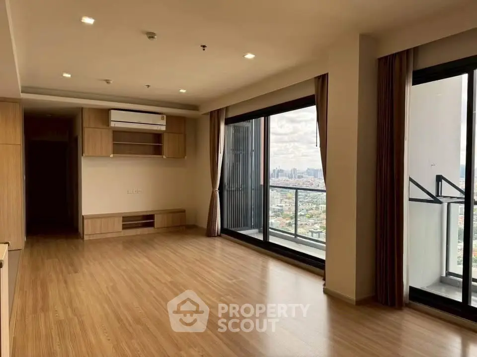 Spacious modern living room with large windows and city view balcony.
