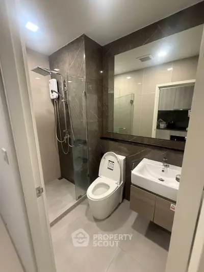 Modern bathroom with glass shower and sleek fixtures in contemporary apartment.