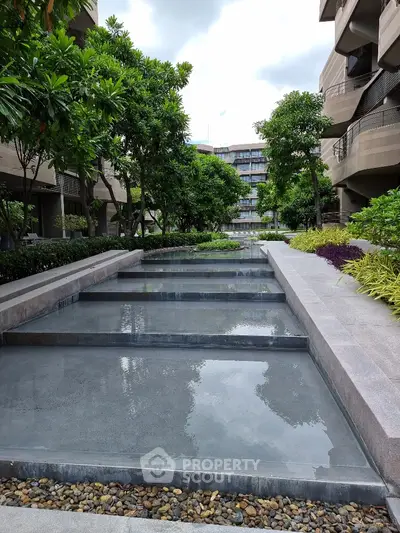 Luxurious modern apartment complex with lush gardens and serene water features.