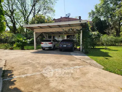 Spacious carport with two cars in a lush green garden setting