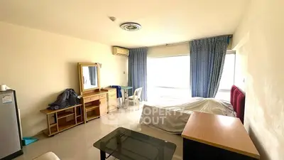 Spacious bedroom with large window and minimalist furnishings in modern apartment.