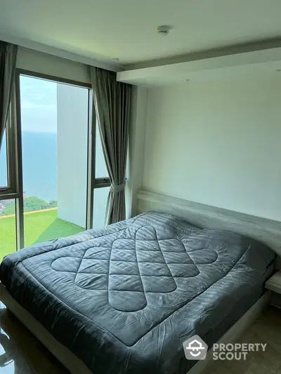 Spacious bedroom with large window offering stunning ocean views, natural light, and a serene atmosphere, perfect for relaxation and comfort.