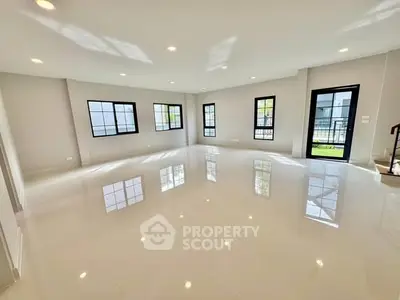 Spacious empty living room with large windows and glossy floors in modern home.