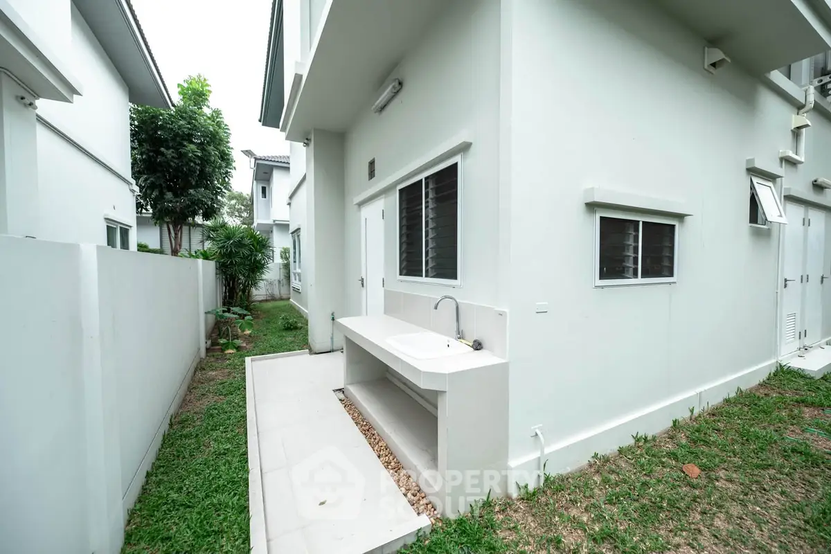 Modern exterior view of a white house with a side yard and outdoor sink area.