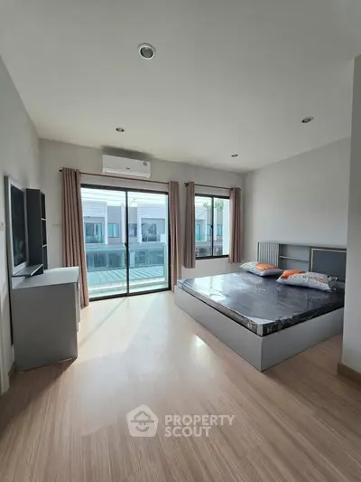 Spacious bedroom with large windows and balcony access in modern apartment