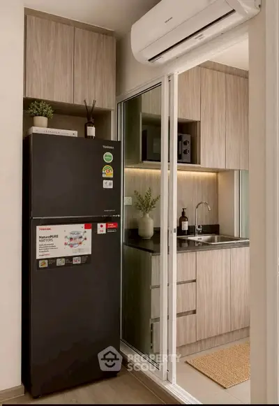 Modern kitchen with sleek cabinetry and energy-efficient refrigerator in a stylish apartment.