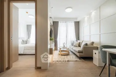 Modern living room with elegant decor and natural light, adjacent to a cozy bedroom.