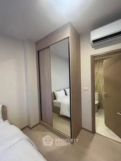 Modern bedroom with mirrored wardrobe and ensuite bathroom in a cozy apartment.