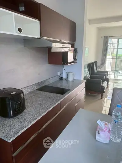 Modern kitchen with sleek cabinets and granite countertops in a bright open-plan living space.