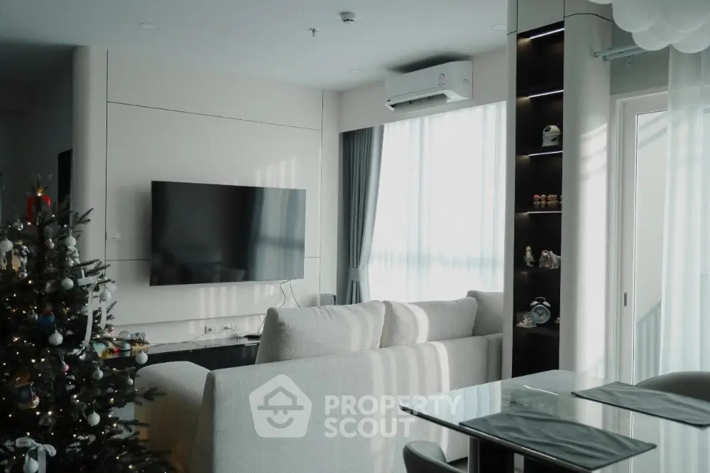 Modern living room with Christmas tree, wall-mounted TV, and large windows