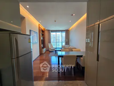 Modern living room with wooden flooring and city view, featuring elegant furniture and ambient lighting.