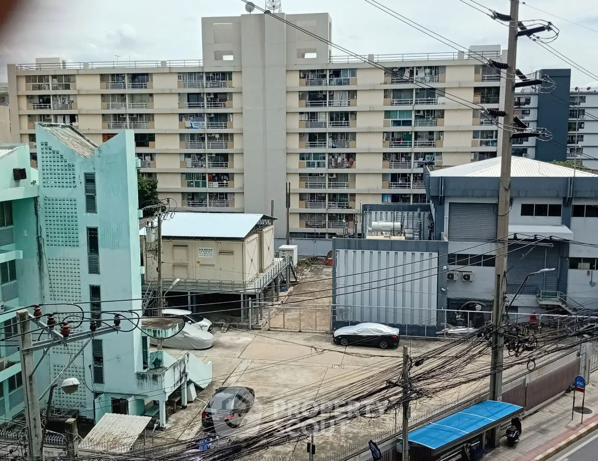 Urban apartment complex with parking area and surrounding buildings, showcasing city living environment.