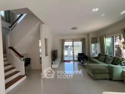 Spacious modern living room with large windows and stylish green sofa