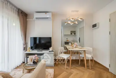 Modern living room with dining area and kitchen in open layout, featuring stylish decor and natural light.